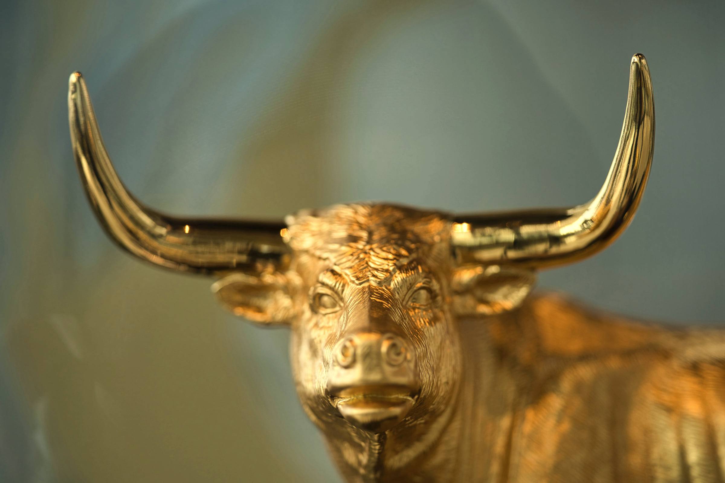 Goldene Bullenfigur mit langen Hörnern, Nahaufnahme vor unscharfem Hintergrund