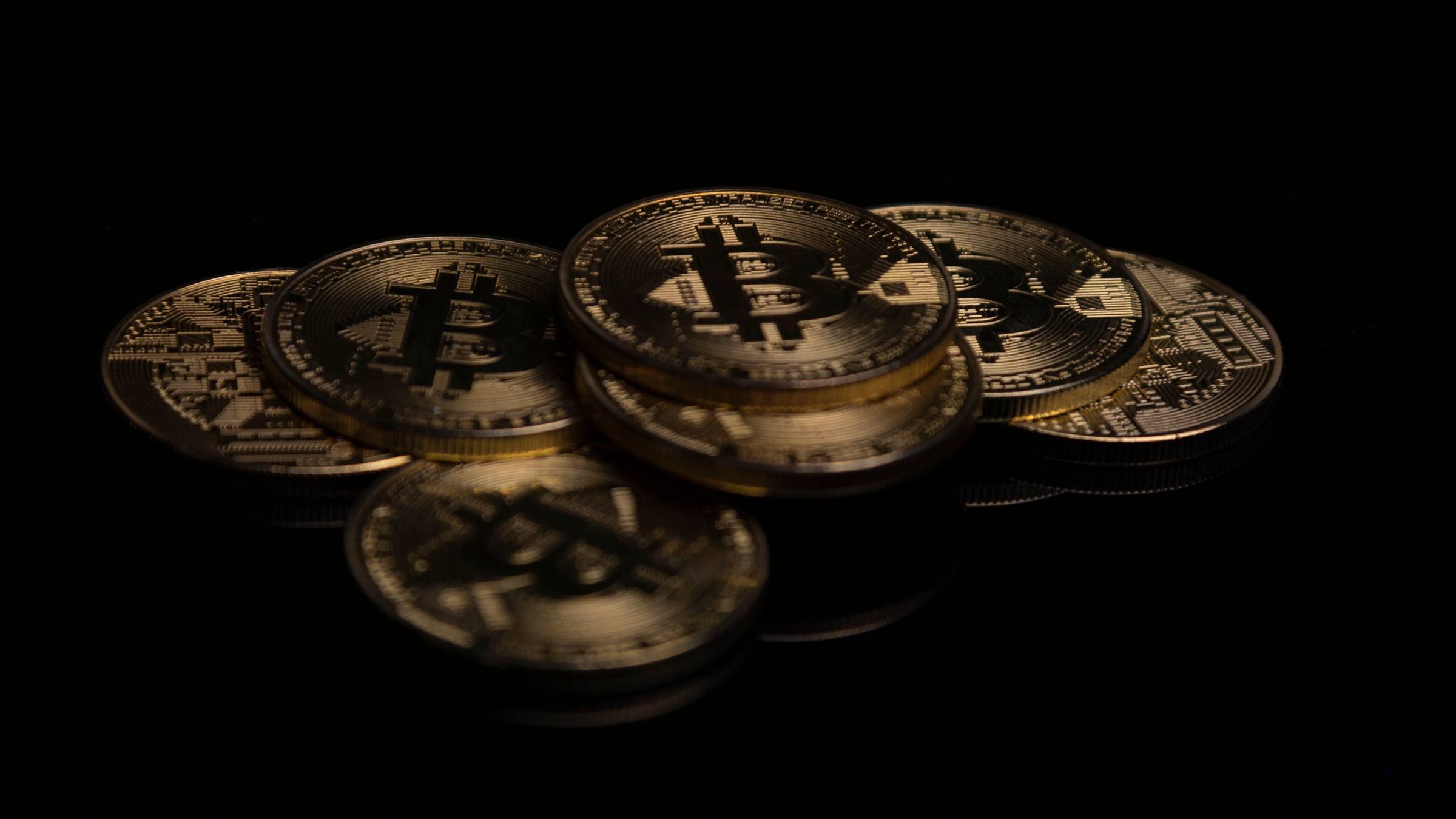Mehrere goldfarbene Bitcoin-Sammlermünzen auf schwarzer Fläche